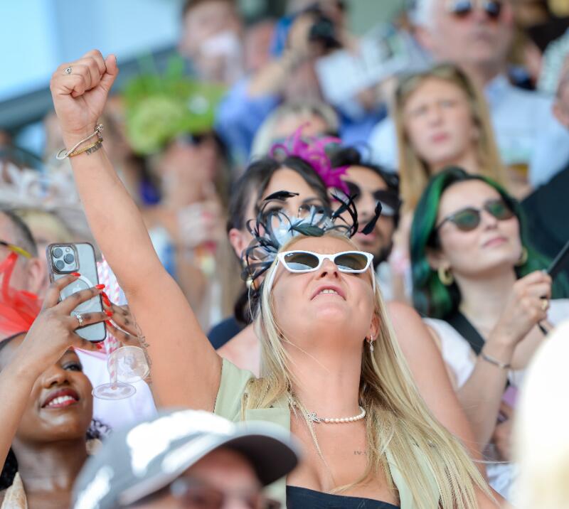 A race goer throws their hand in the air in celebration at Uttoxeter Races