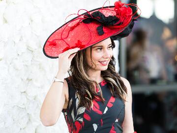 A lady in a red hat shows how to wear a hat at Ladies Day