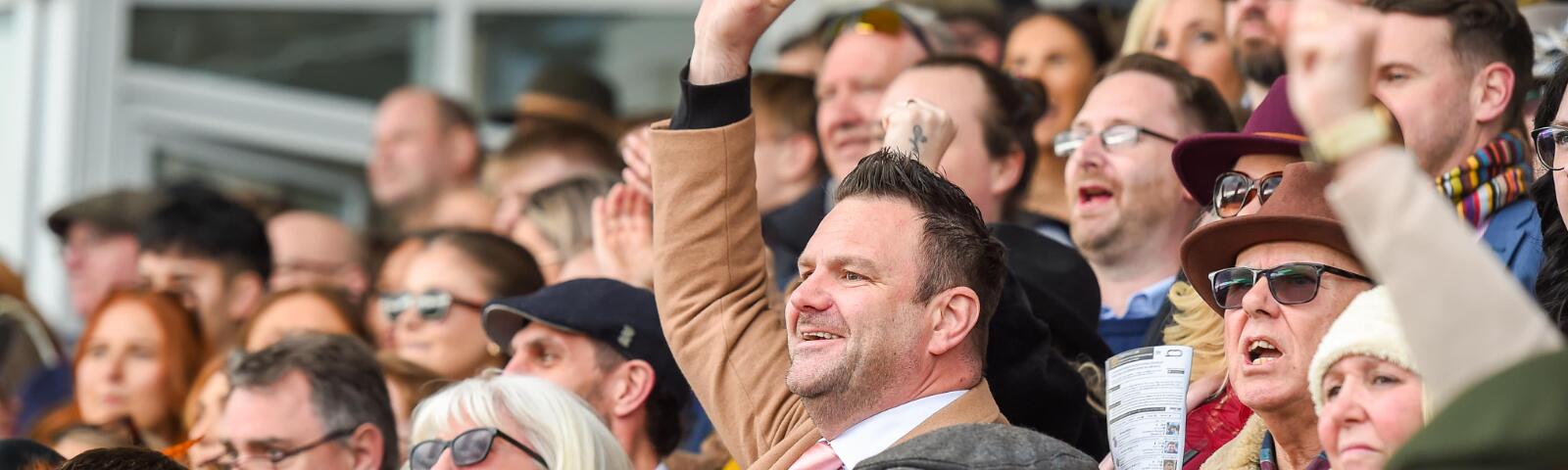 A gent in the crowd at Uttoxeter Races thrusts his hand in the air