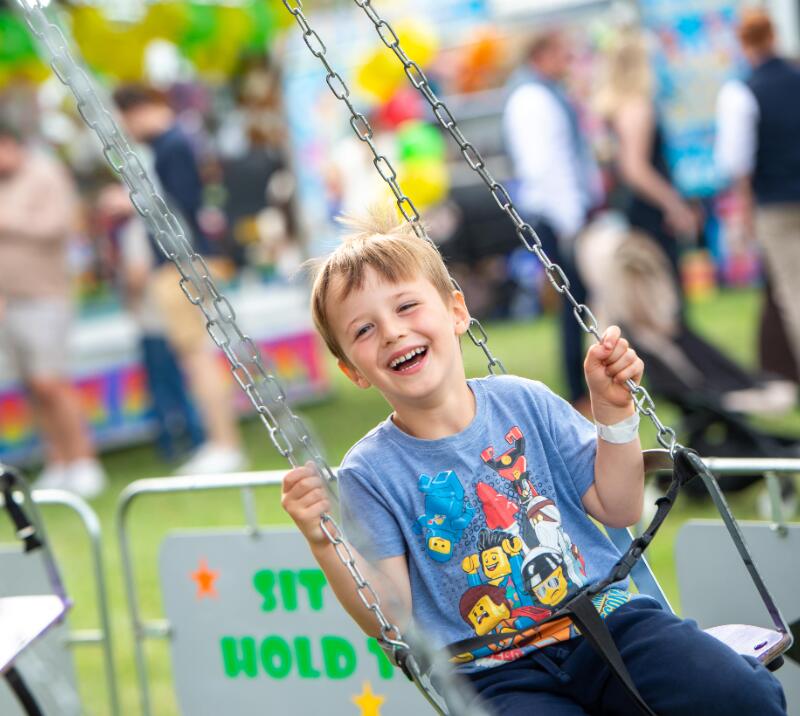 A child smiling on a swing ride at Uttoxeter Races family fun day