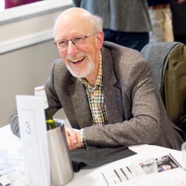 An well dressed gentlemen laughing at his restaurant table