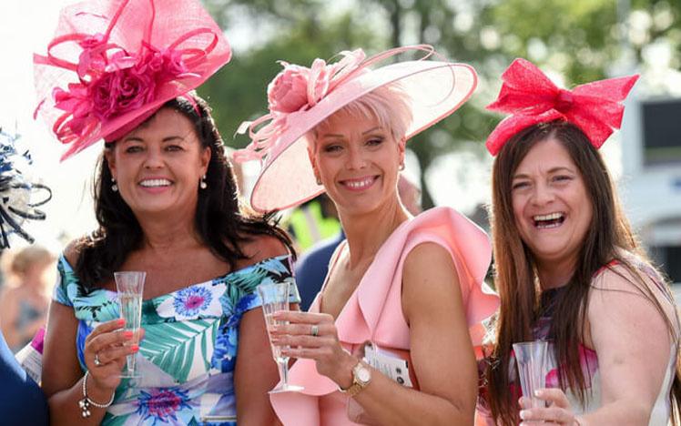Group of dressed up ladies at Uttoxeter Racecourse holding champagne glasses in their hands.