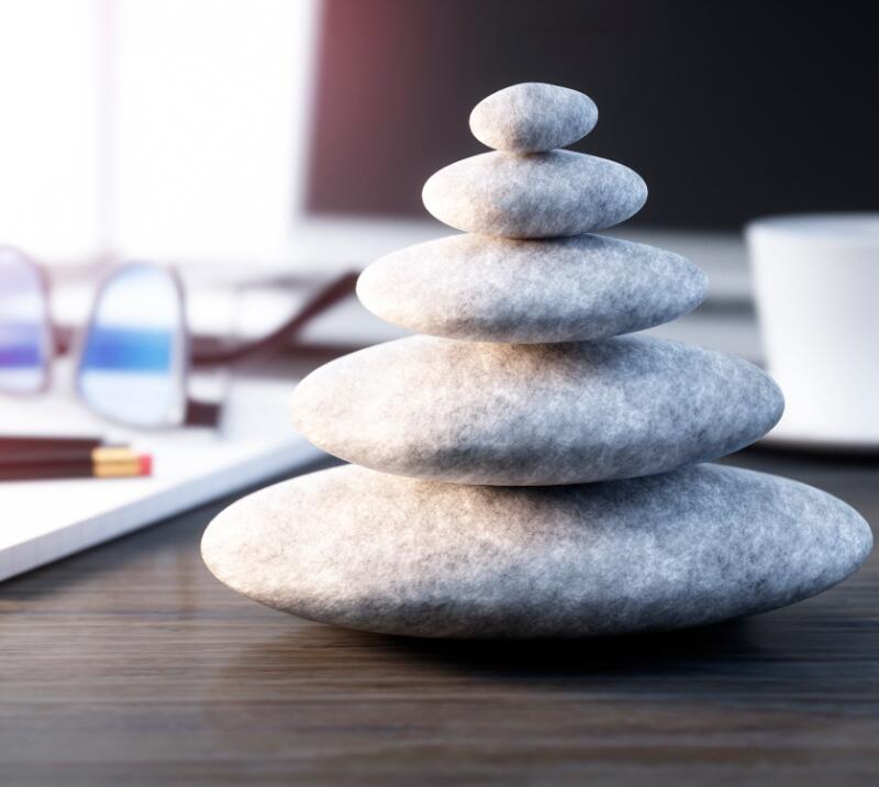 relaxation stones, on desk with glasses, cup, pencils, pens and notebook